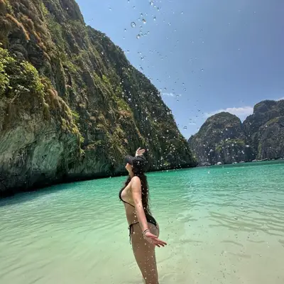Yuvibaby in turquoise water between limestone cliffs.